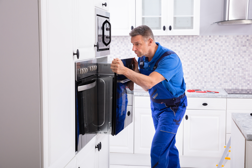 Certified technician inspecting and repairing an oven in a Winnipeg kitchen